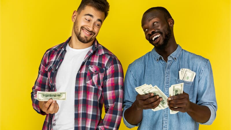 One guy sharing money with another, both laughing