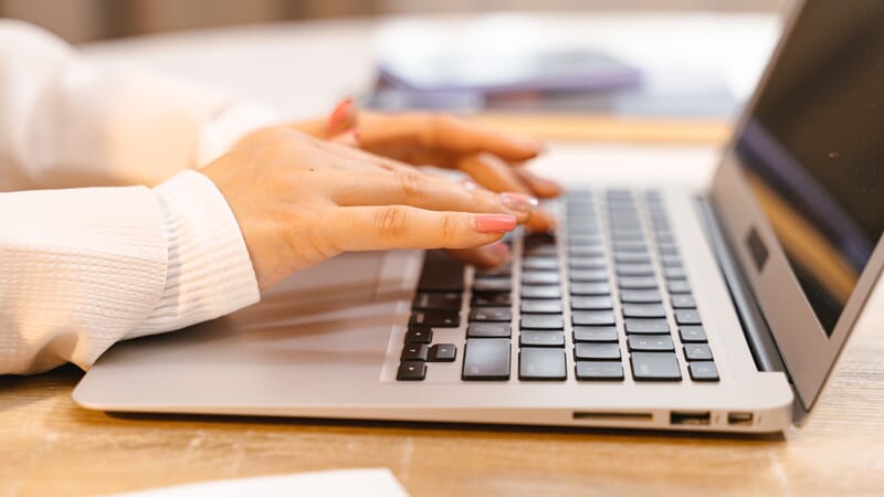 Close-up view of hands typing on a laptop keyboard