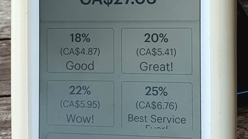 Photograph of a card payment terminal showing four percentage tipping options (18, 20, 22, and 25%) where each option is associated with a rating (good, great, wow, best service ever!), a custom tip option, and a skip option
