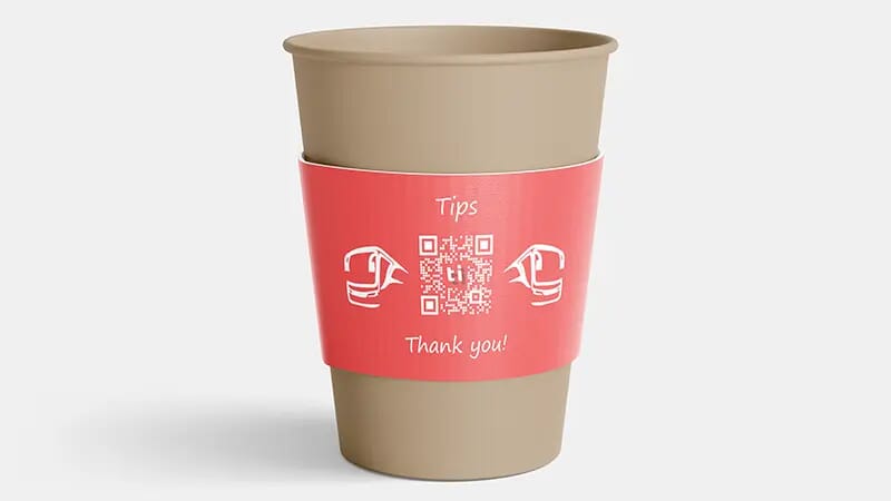 A coffee cup doubling as a tip jar for use by a coach driver. The sleeve shows that this is a tip jar, shows the company logo, and importantly also shows a QR code. When the customer scans the QR code they are taken to an electronic payment form so that they can securely pay a tip using their credit card.